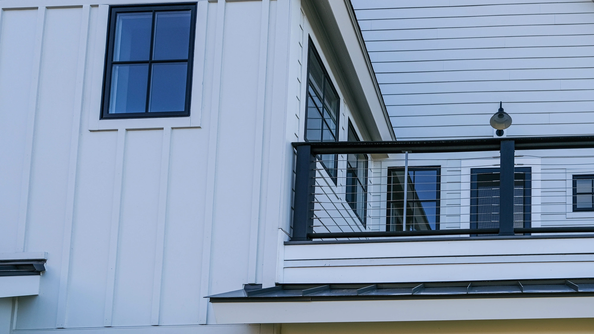 The exterior of a home with white siding and a black railing