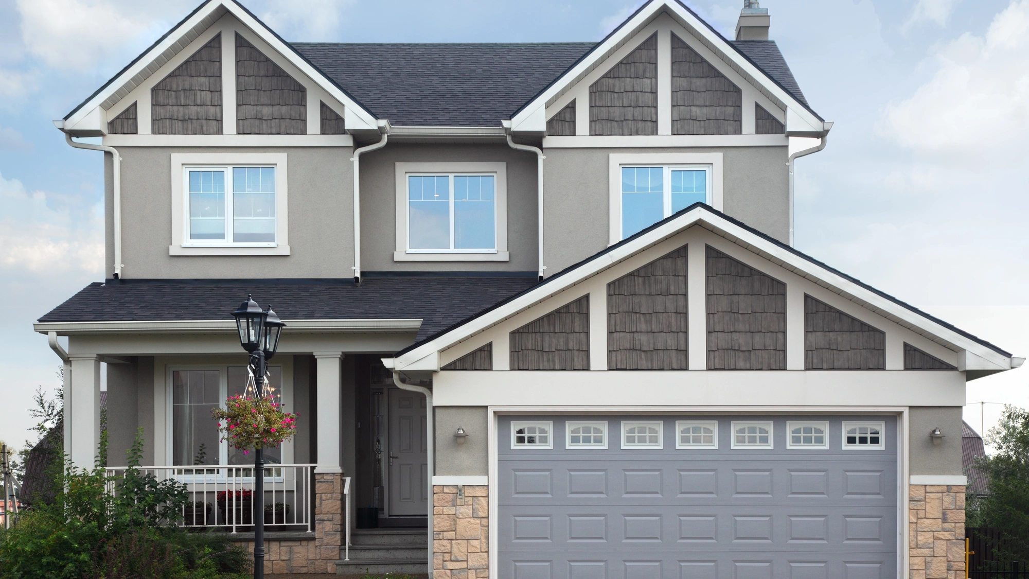 A large home with gray and brown siding and a gray shingle roof