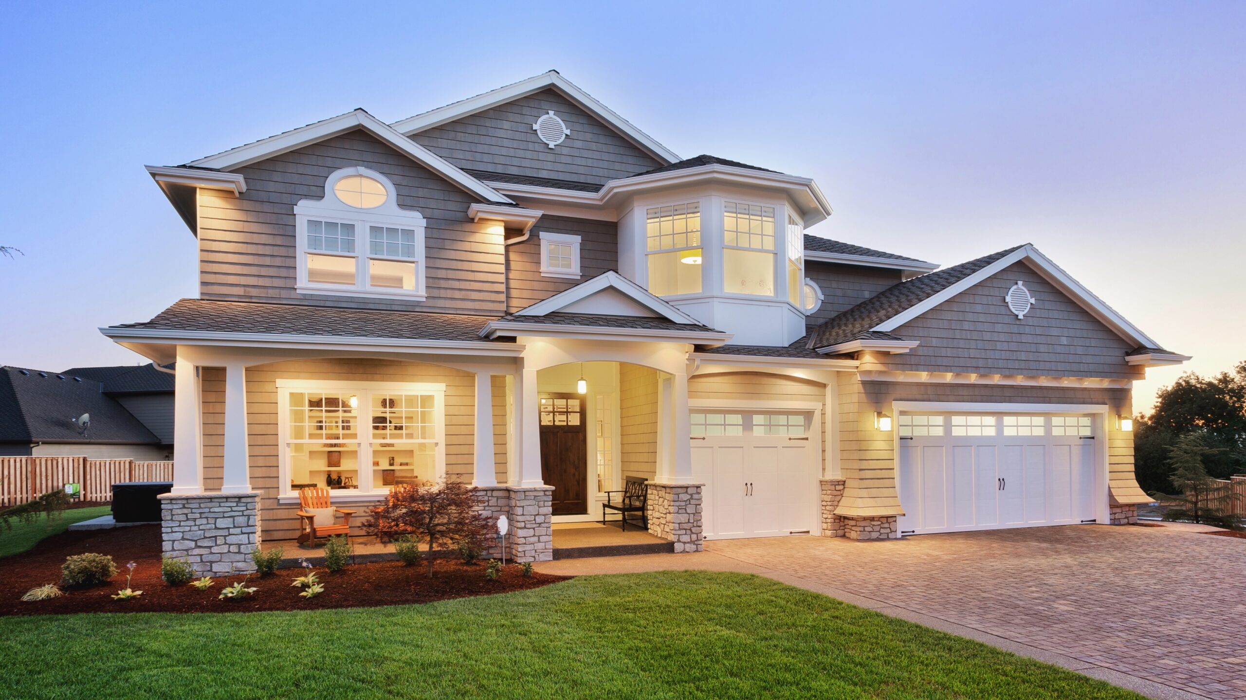 A large home with stone siding and a gray shingle roof