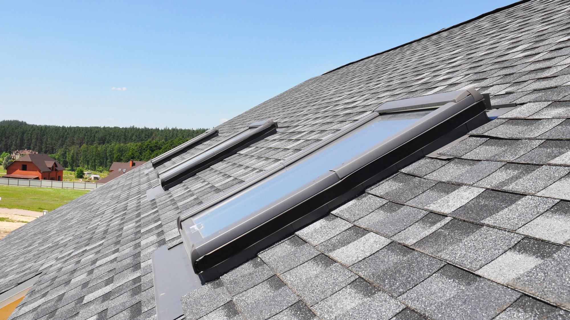 Closeup of a gray shingle roof with skylights