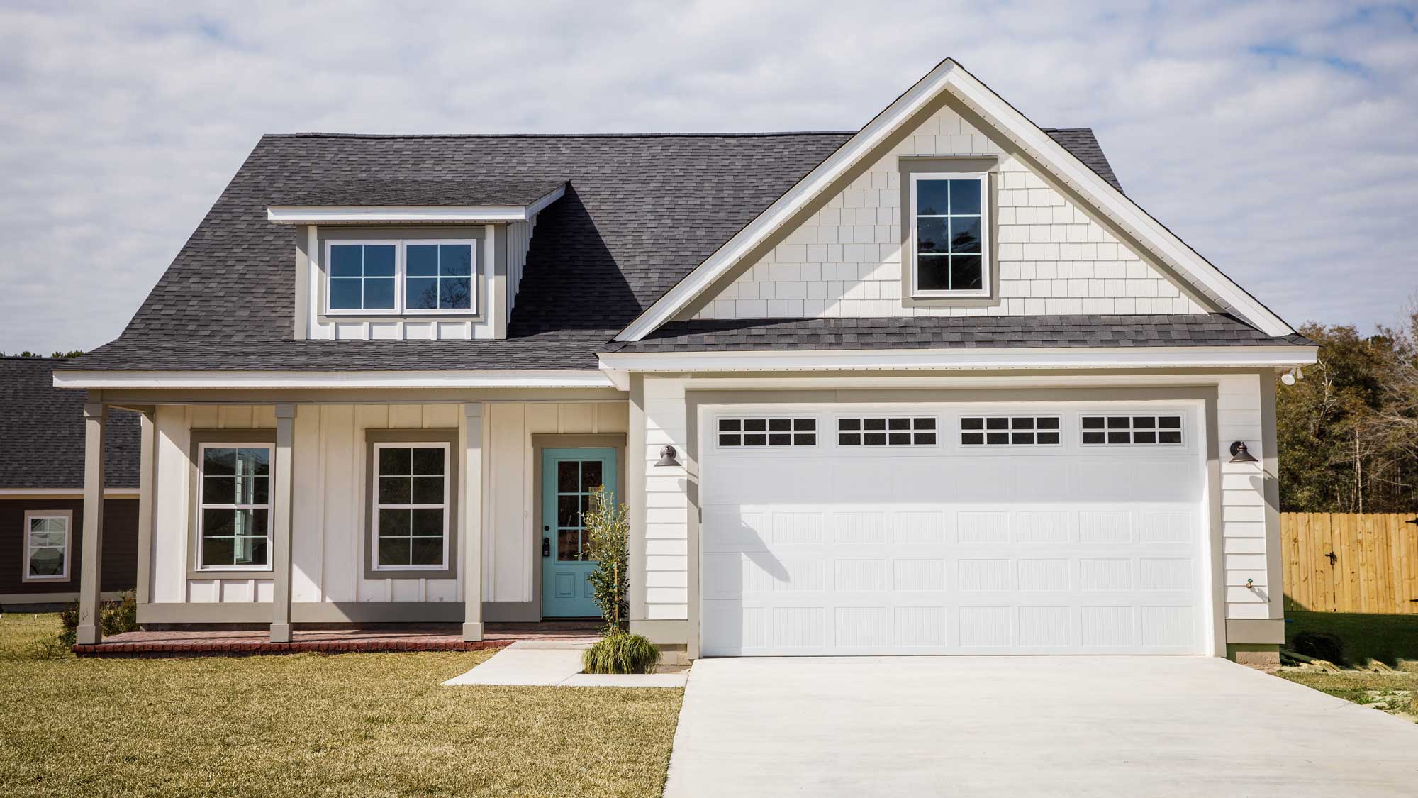 A white-sided home with gray shingle roofing and newly installed windows