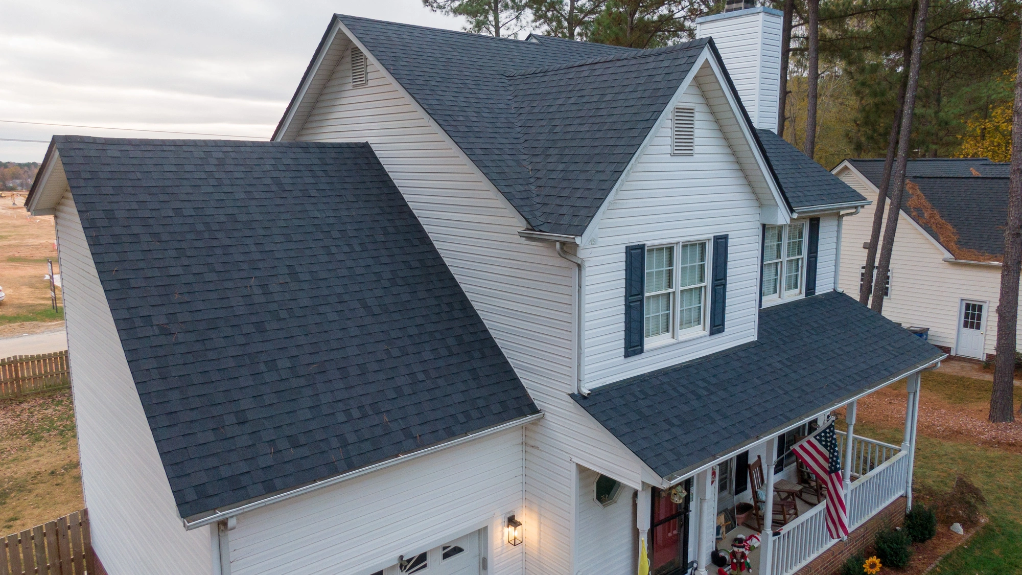 A large white-sided home with gray shingle roofing