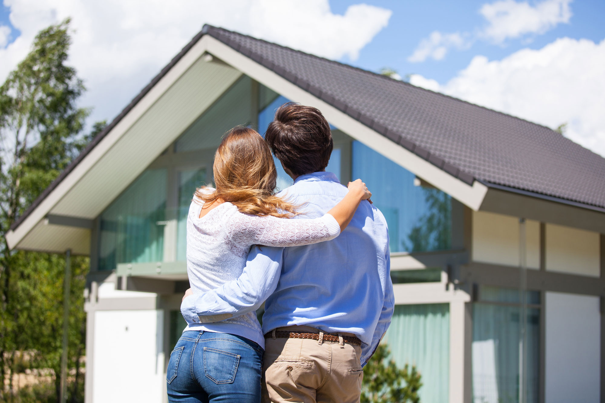 Couple hugging in front of house