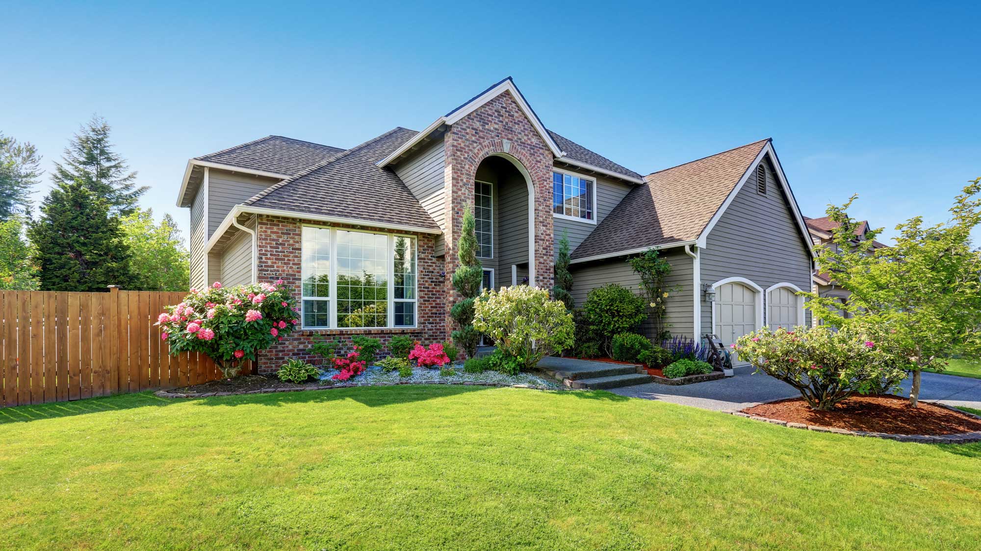 A brick home with a gray shingle roof and custom windows