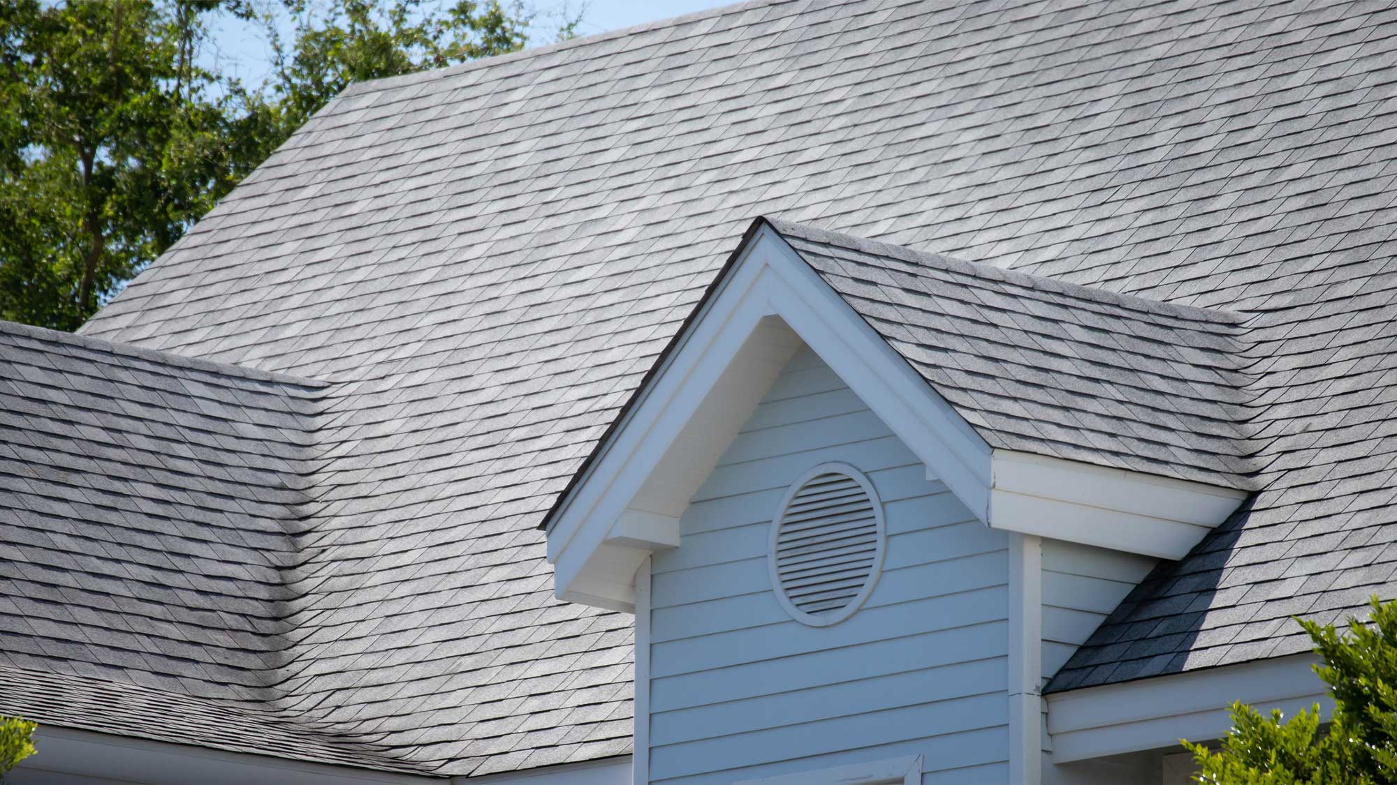 Closeup of a gray shingle roof with dormers