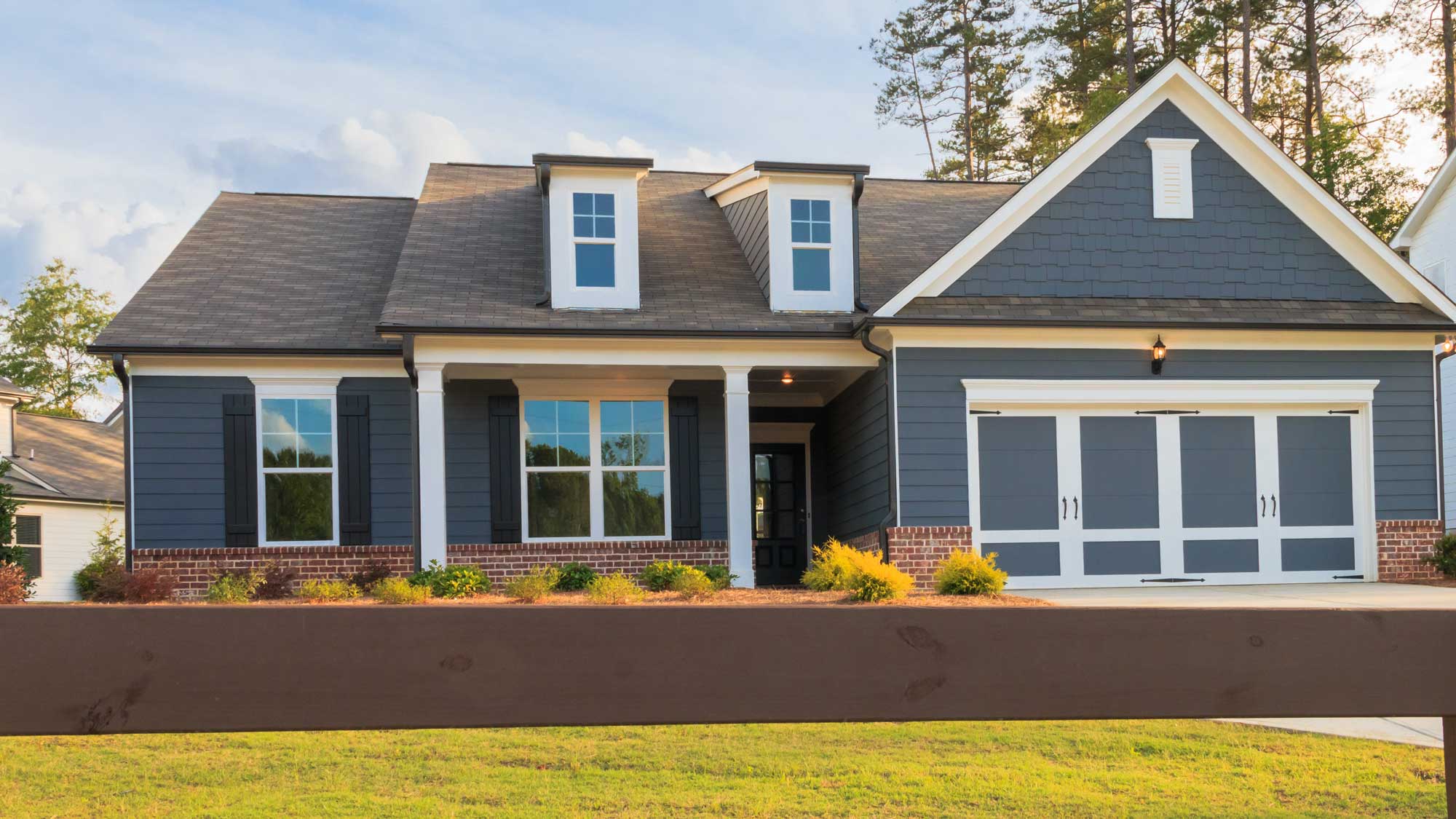 A home with gray siding, gray shingle roofing, and two dormers