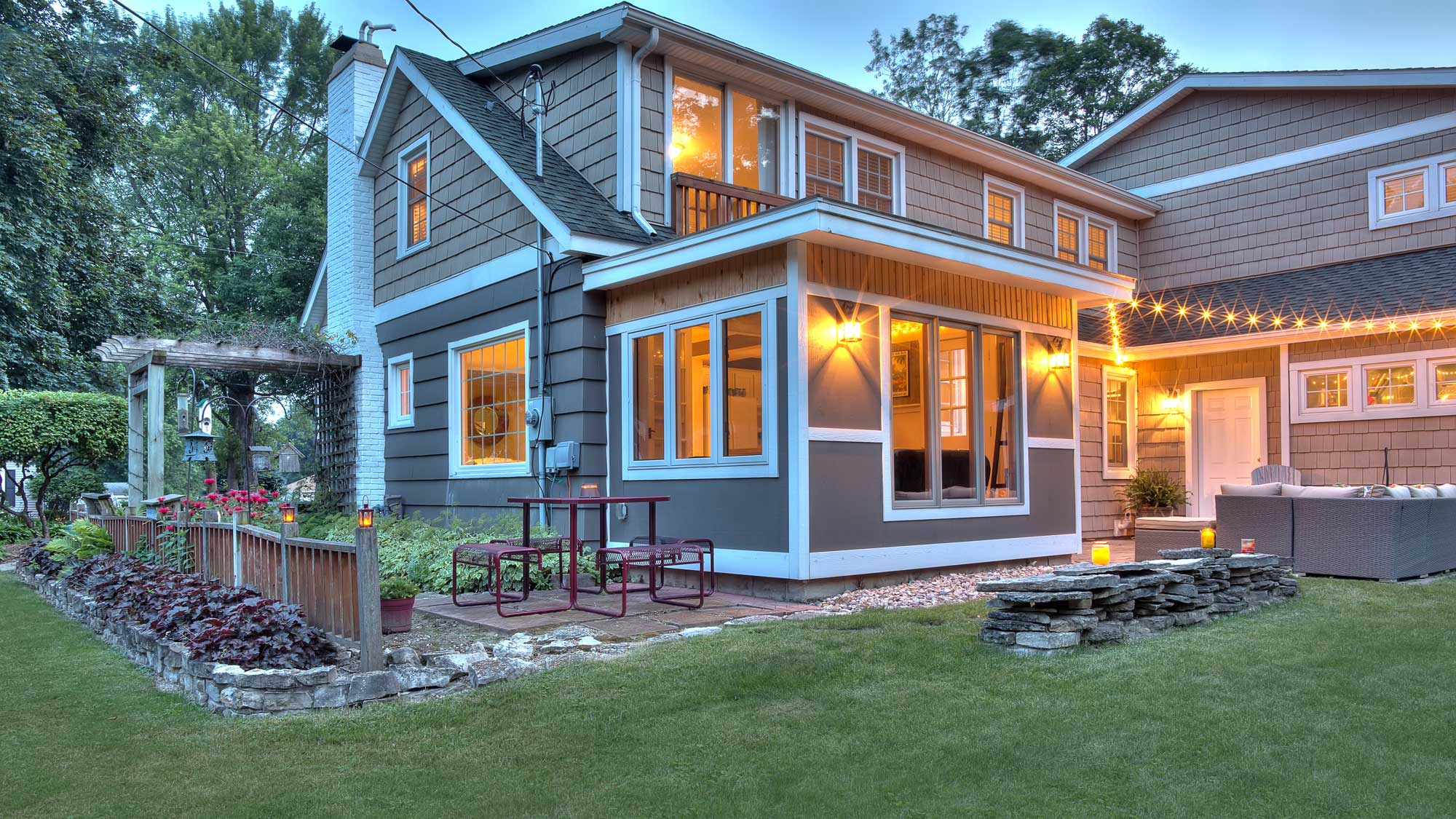 A tan-sided home with white trim at dusk