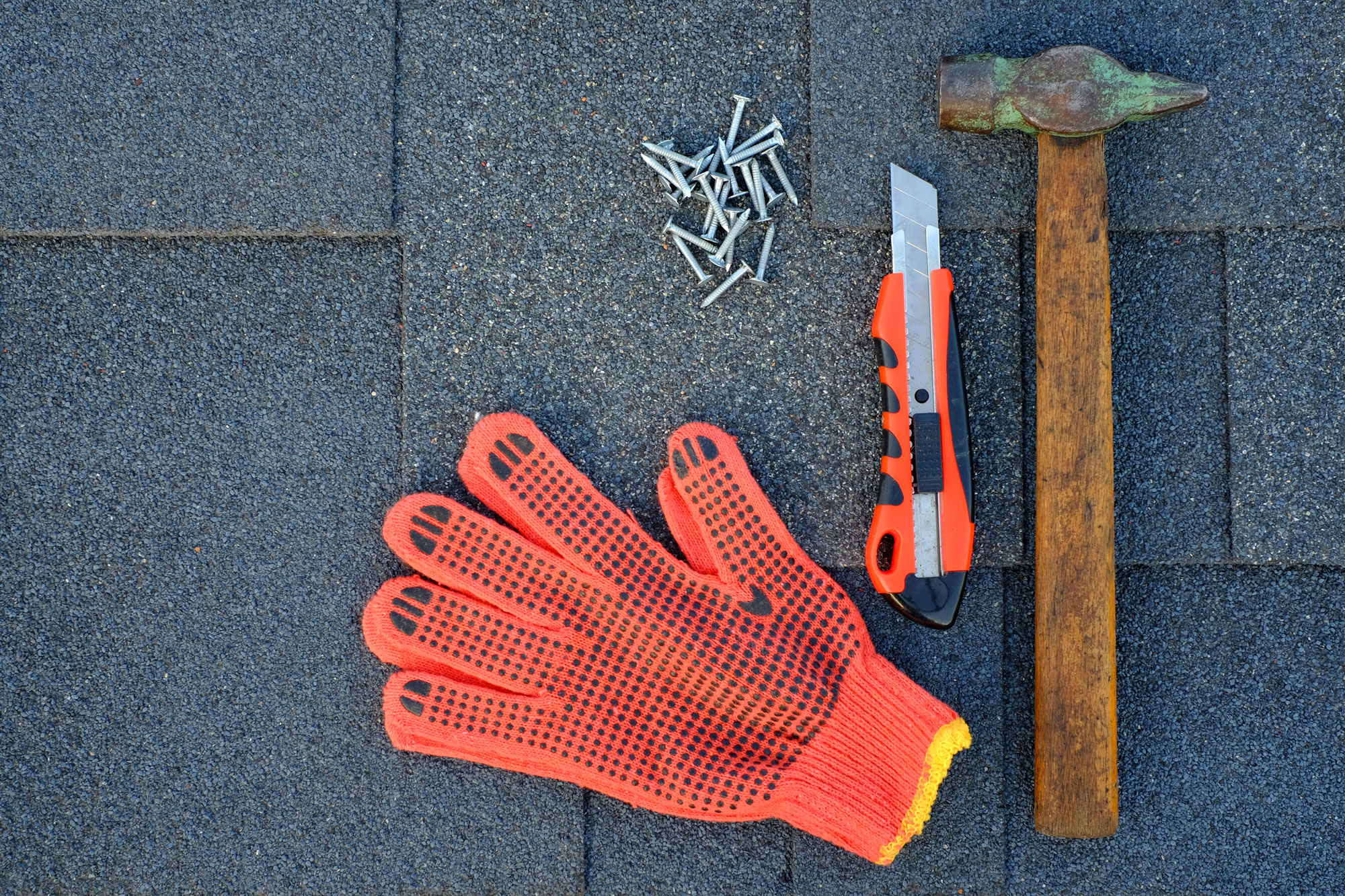 Roof repair tools on asphalt shingle background