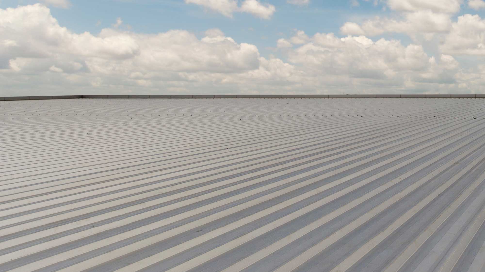 Closeup of a brand-new commercial roof with blue sky and light clouds in the background