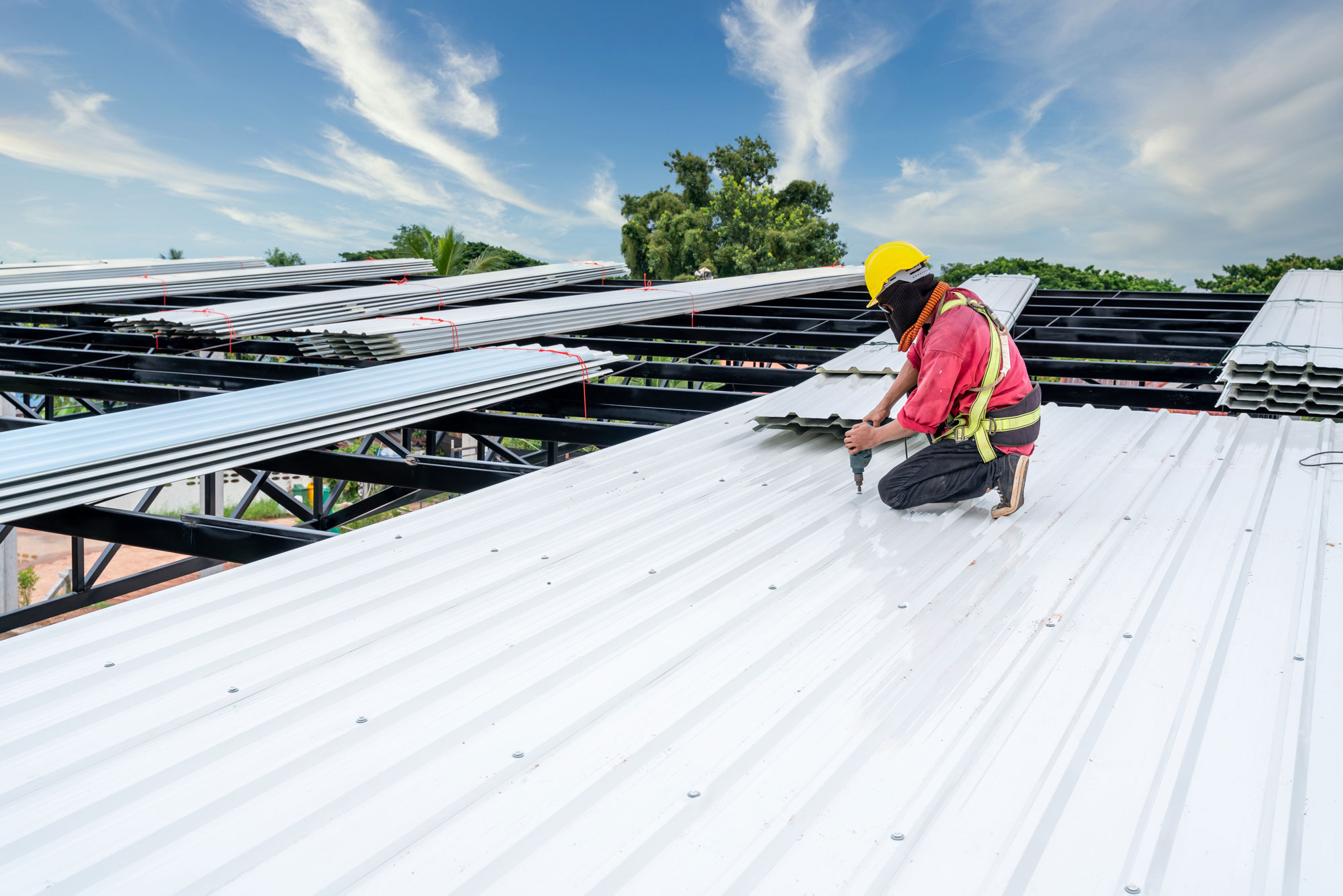 Roofer installing white metal commercial roof