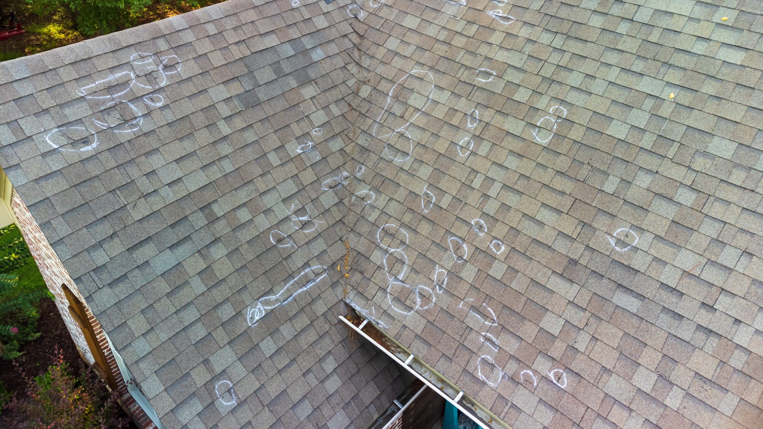 A shingle roof marked where hail damage occurred