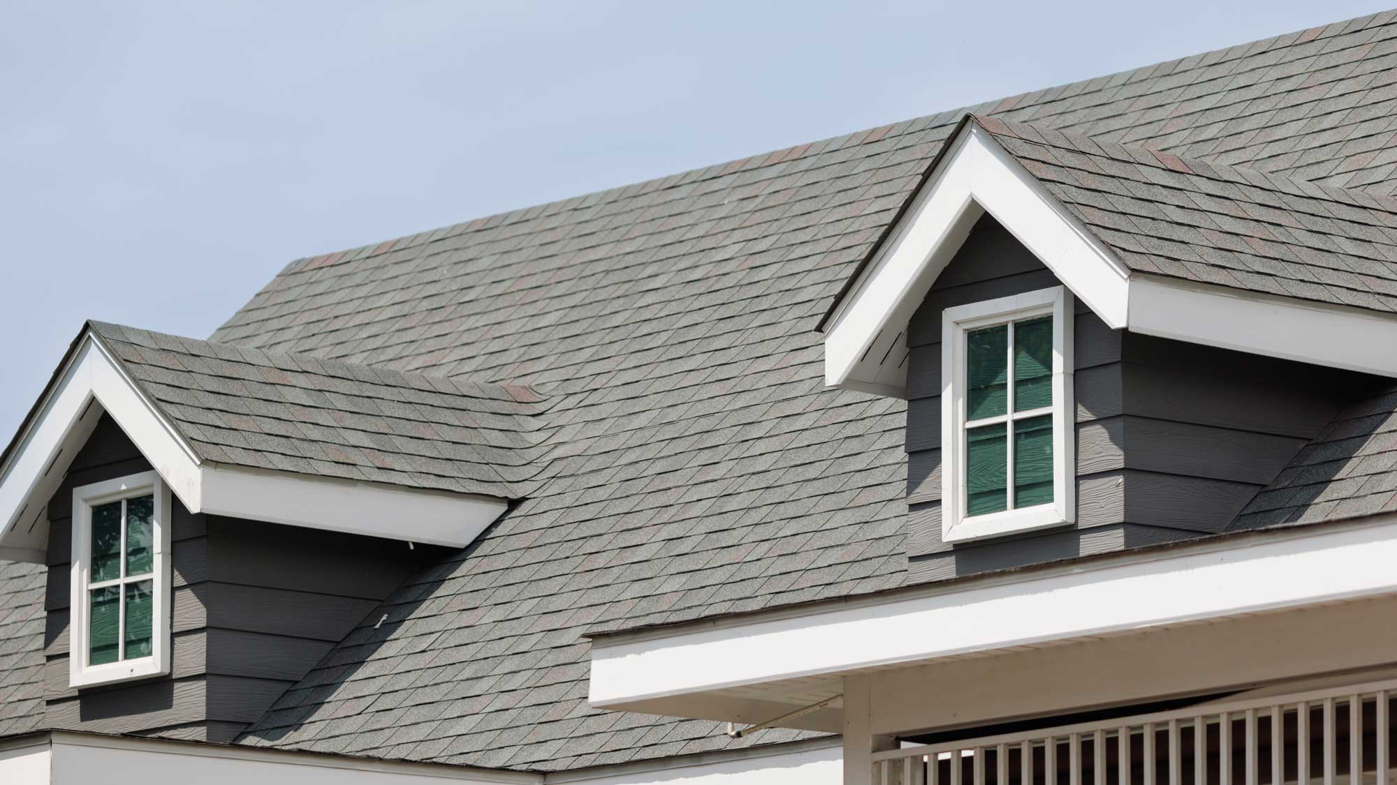 A pristine gray shingle roof with two dormer windows