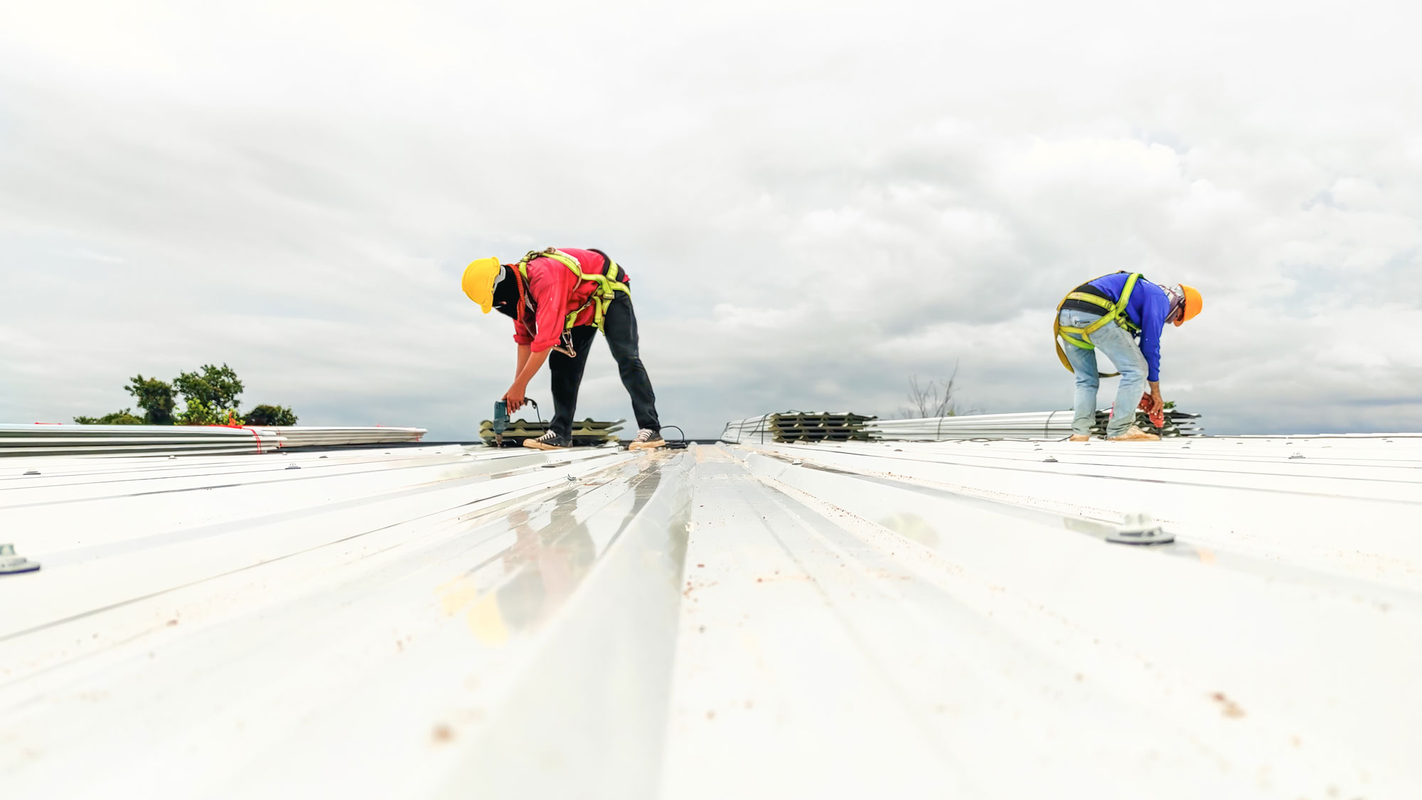 Two roofers repairing white metal commercial roof