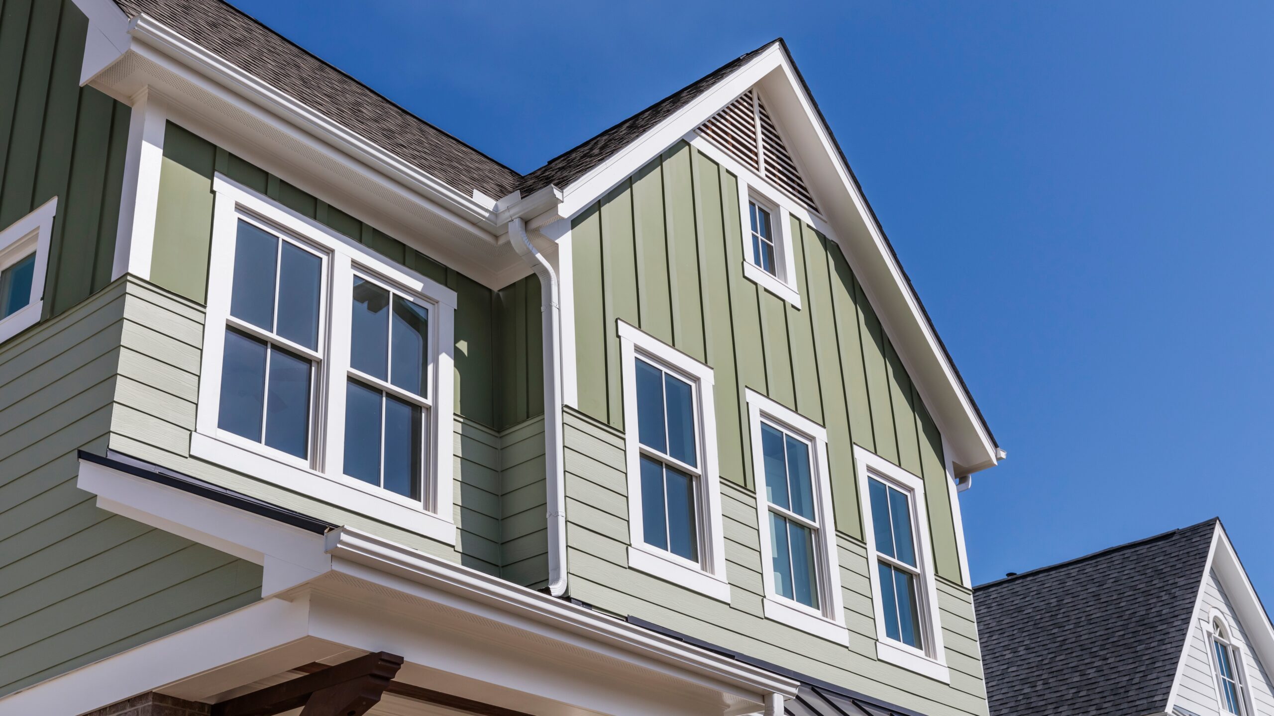 A home with green siding, white trim, and new windows