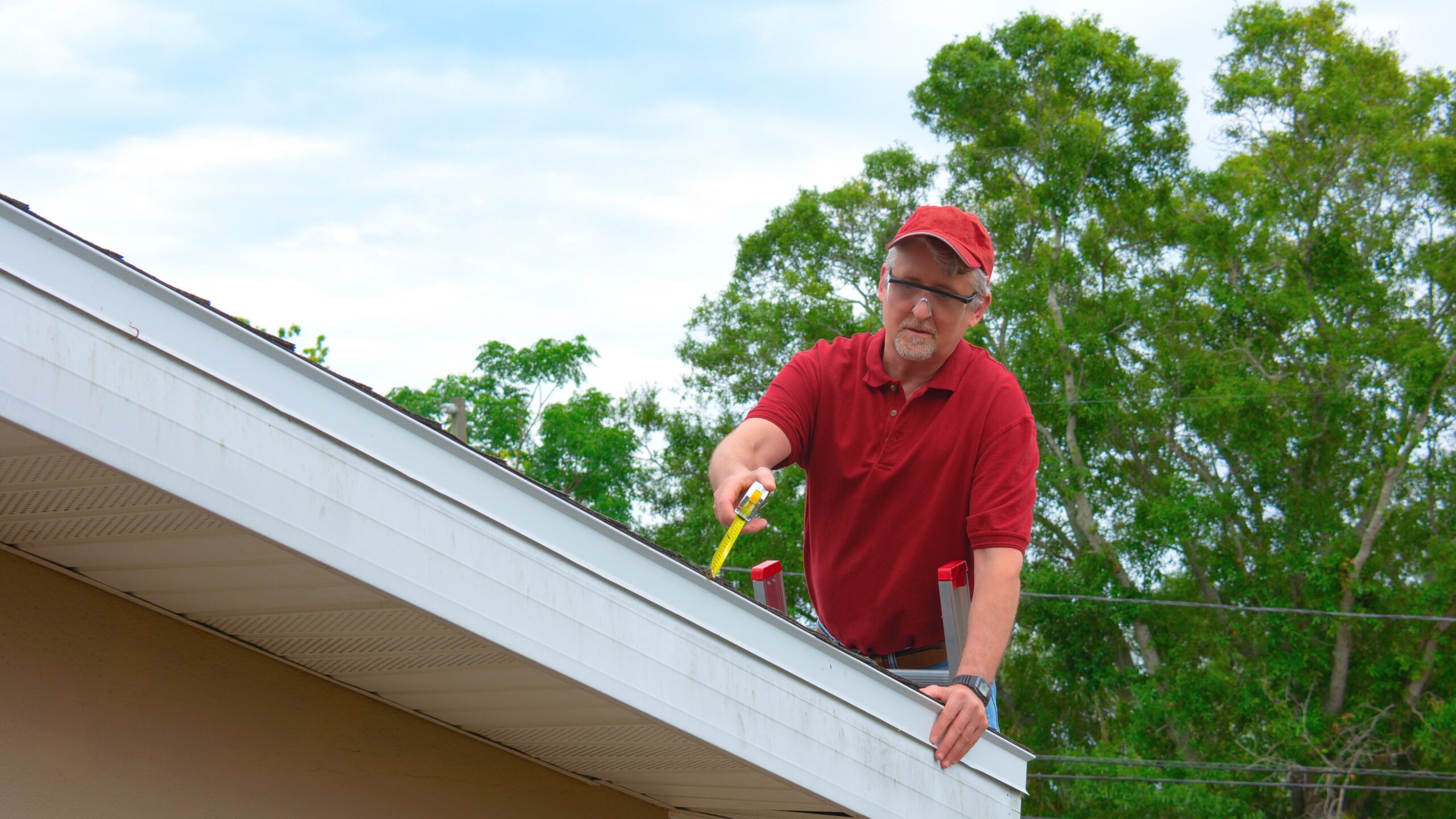 A roofer in a red shirt completes a roof inspection