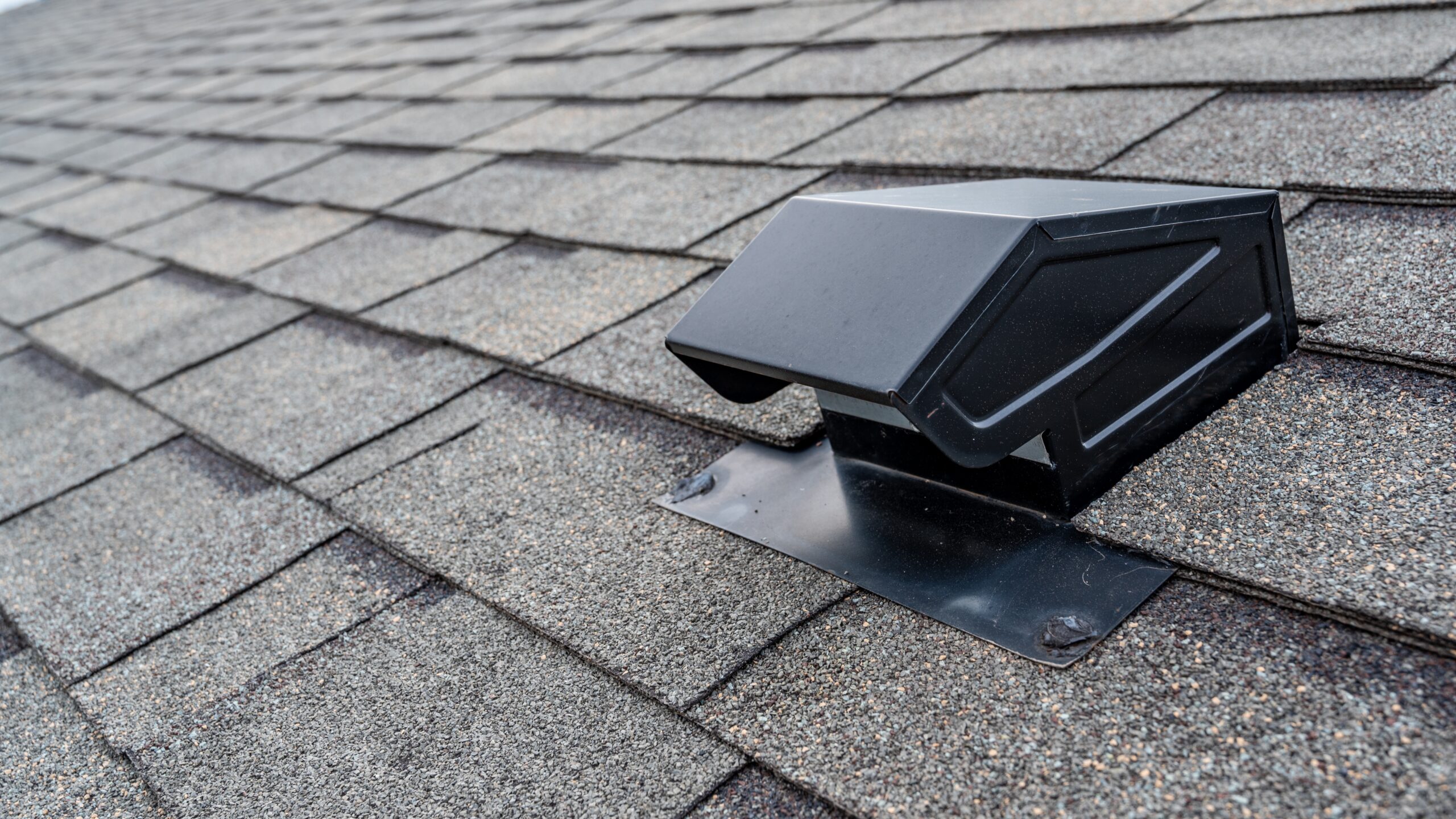 A gray shingle roof with a vent