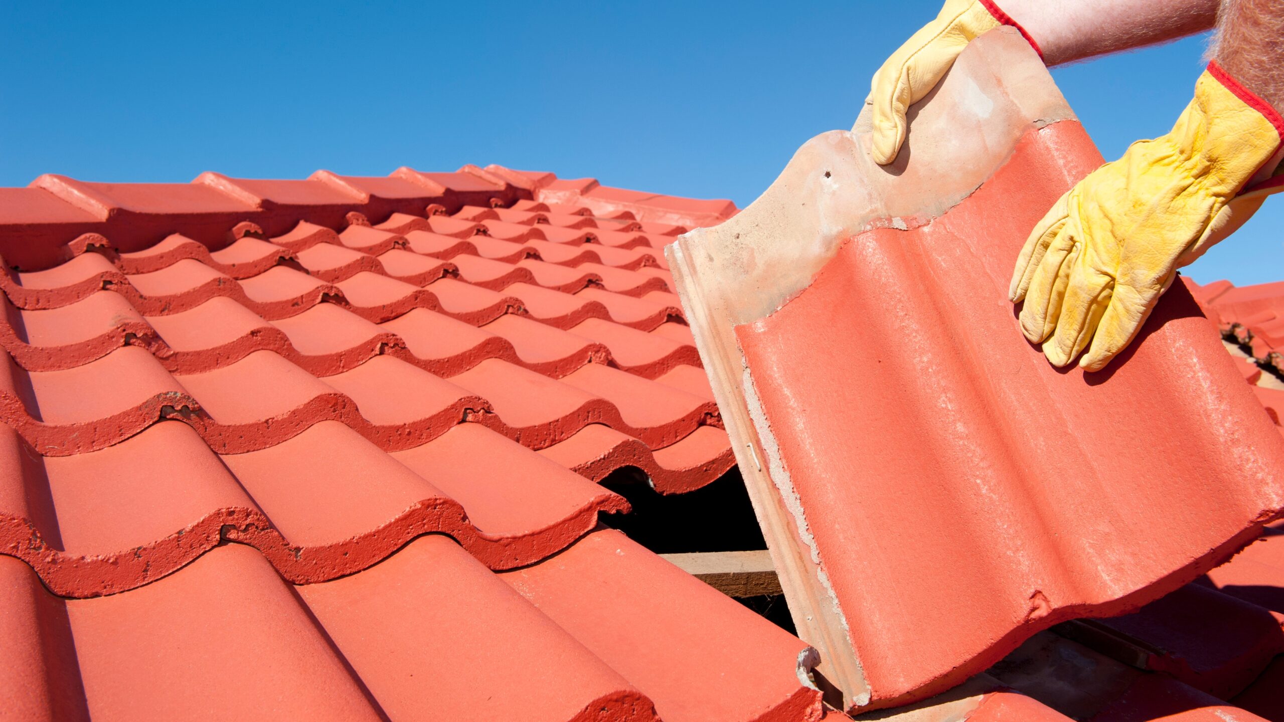 A roofer repairs a tile roof