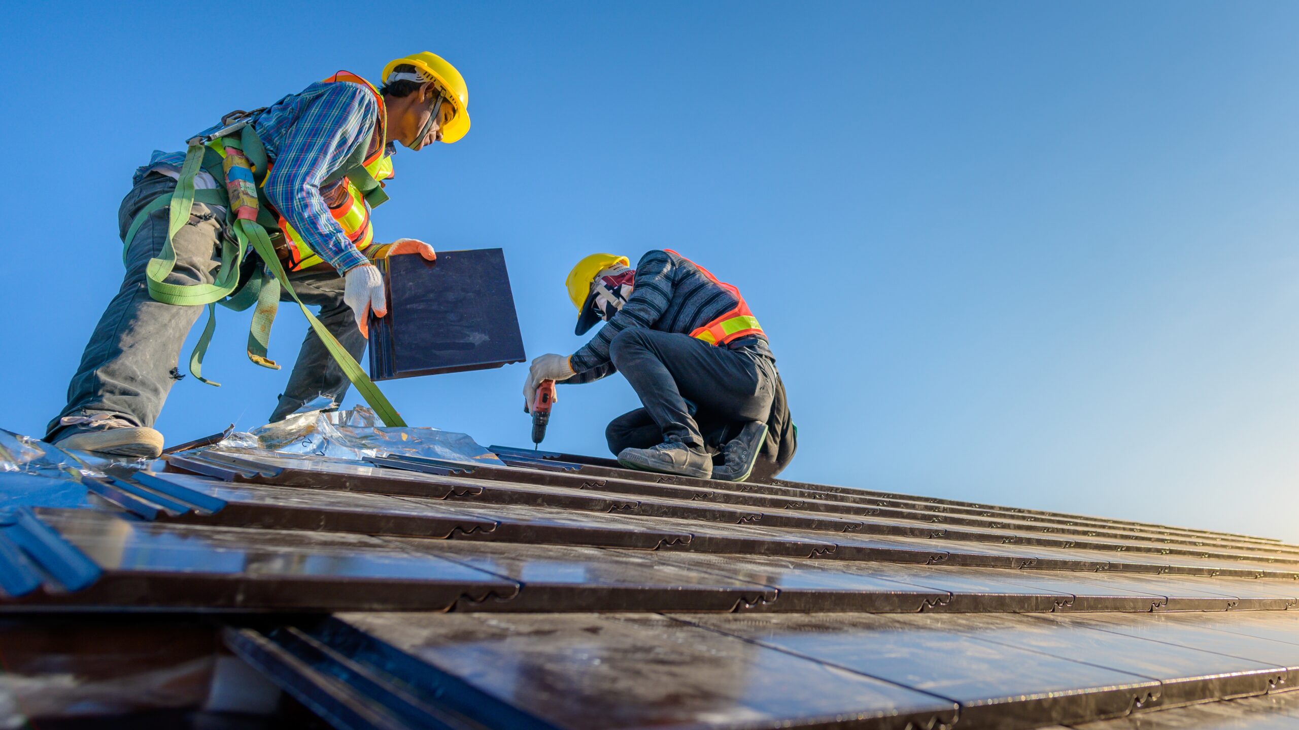 Two roofers repair a slate roof