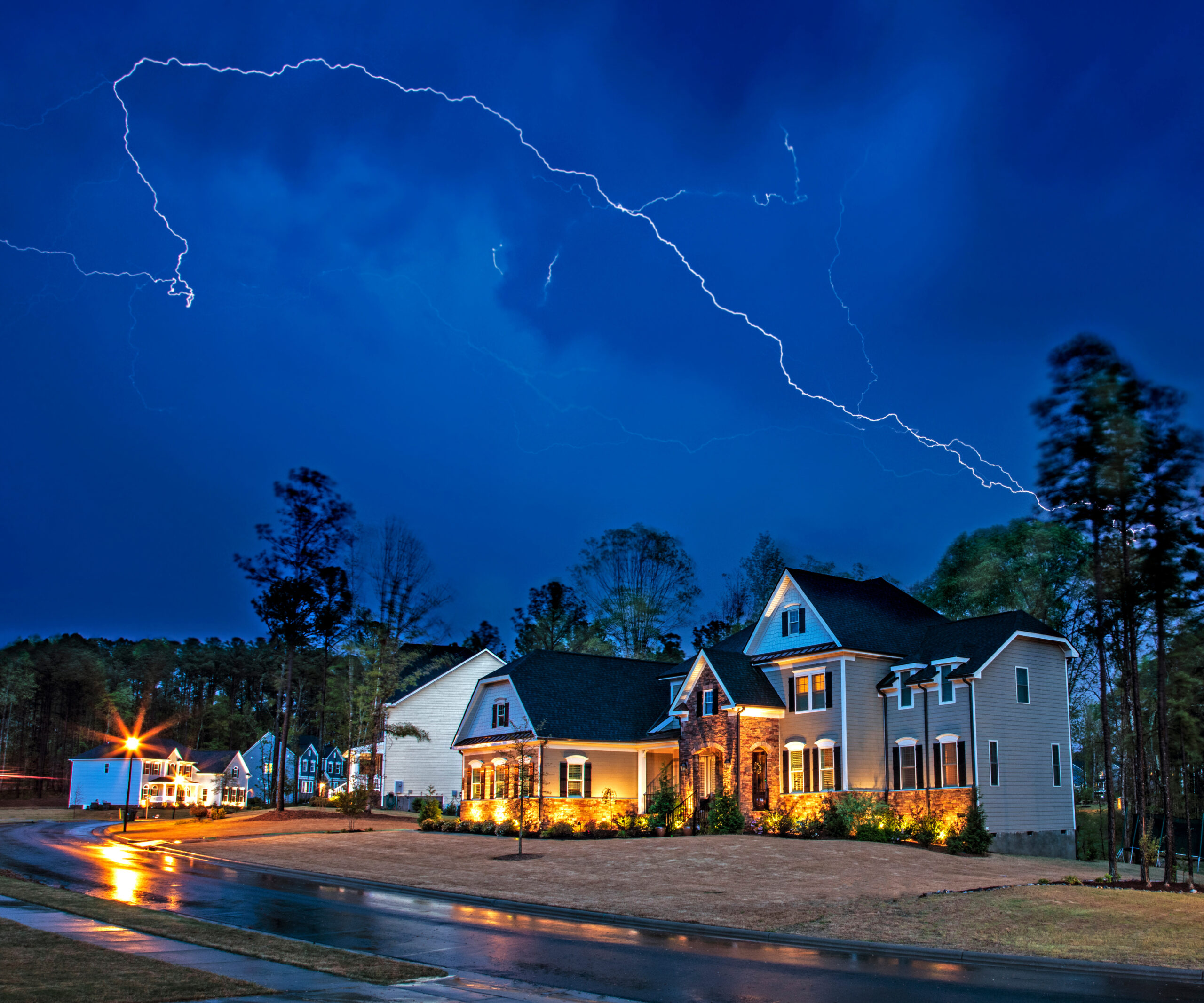 Lighting strikes over a suburban neighborhood at night