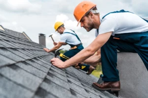 Two roofers nailing shingles