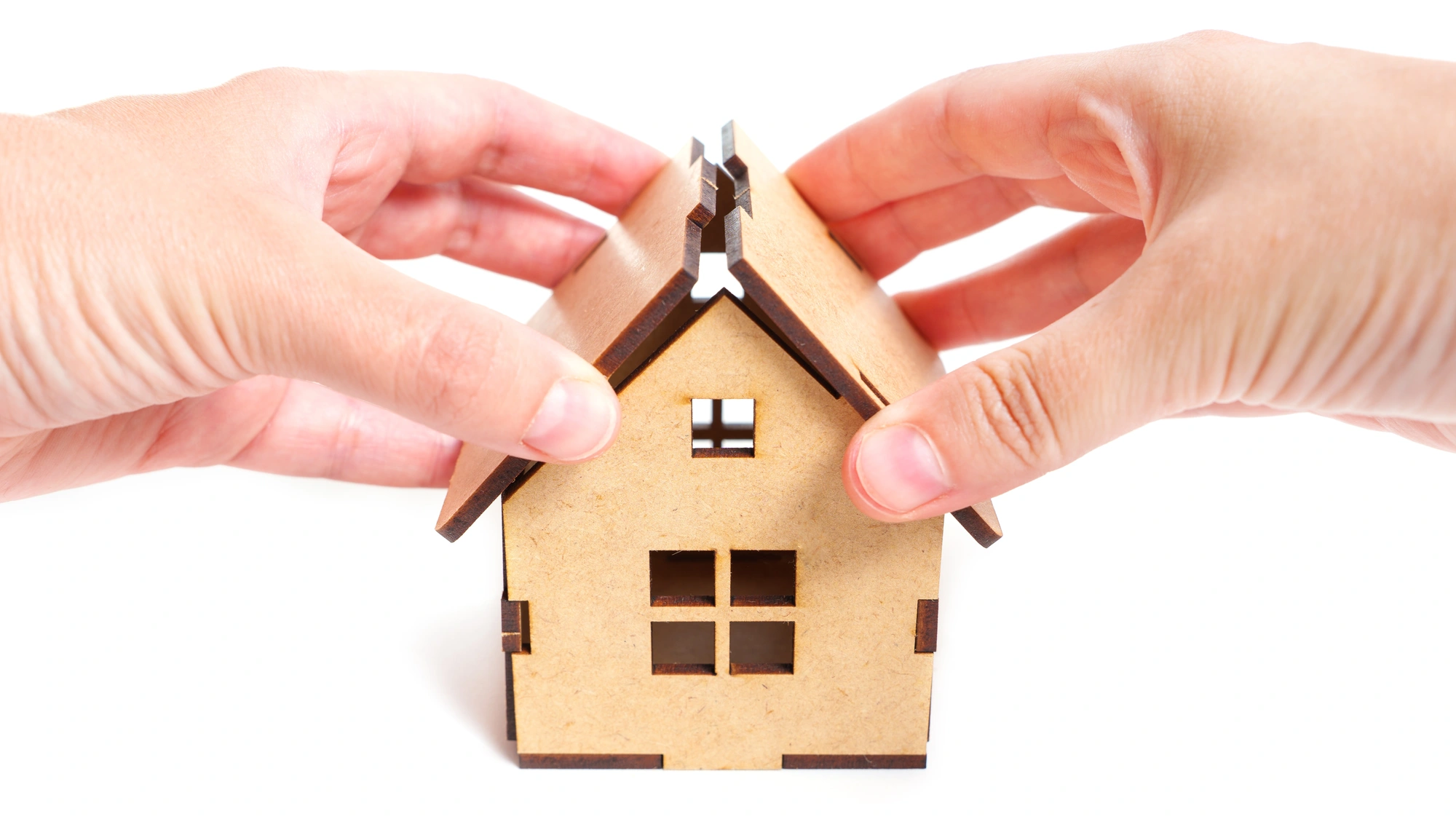 Two hands attach the roof of a model house