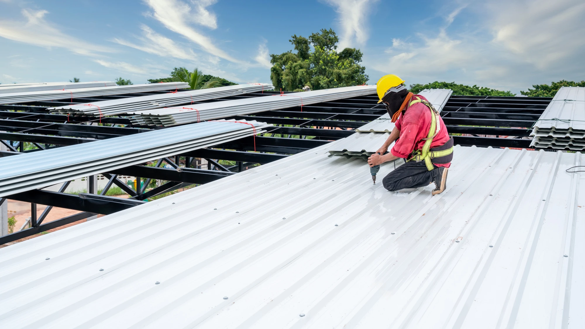 Roofer installing white metal roof