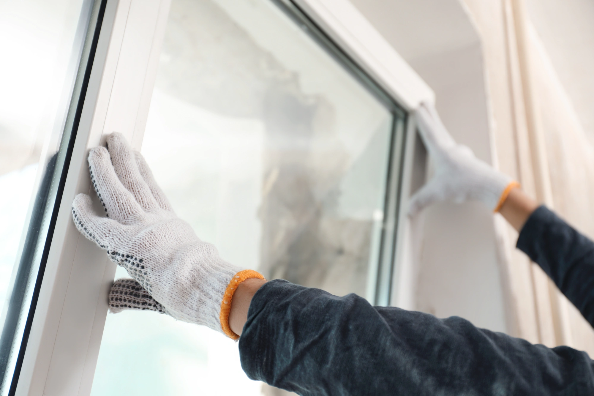 Hands installing window with white frame